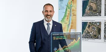 יועץ השקעות מציג תיק השקעות בקרקעות על רקע מפת ישראל ותוכניות מתאר